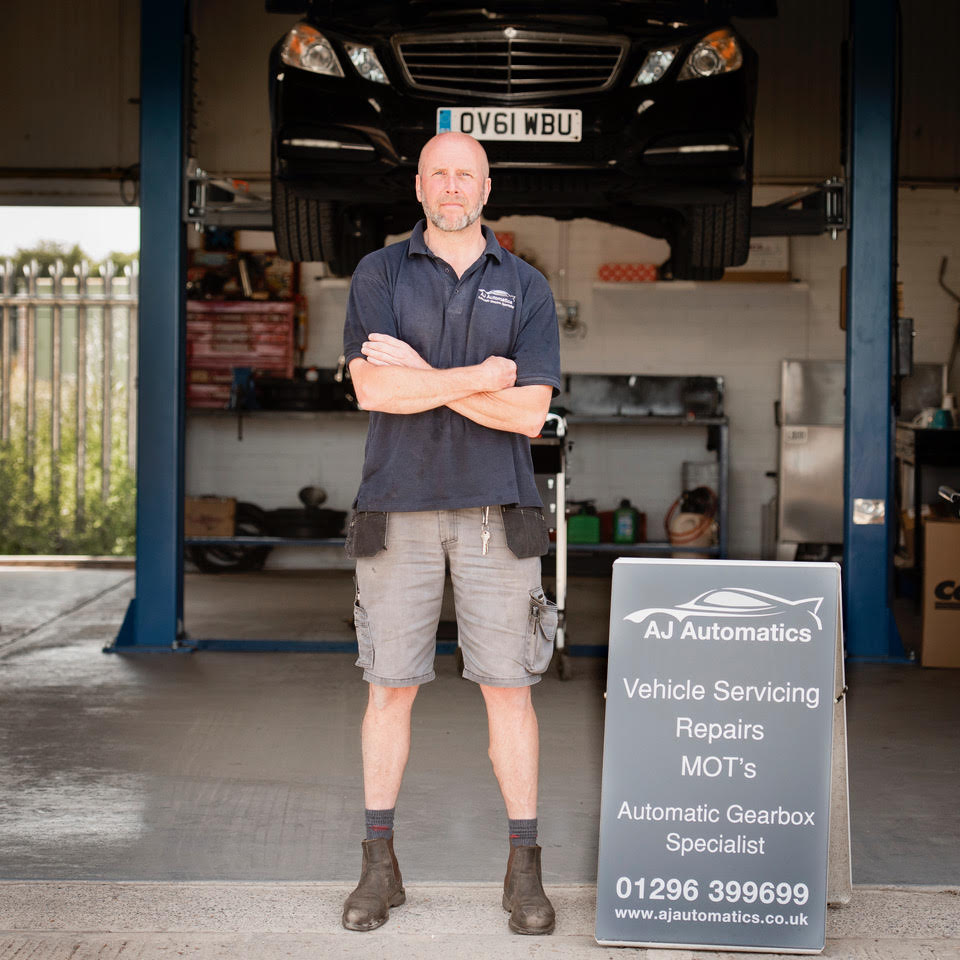 mechanic stood in front of a car on a ramp