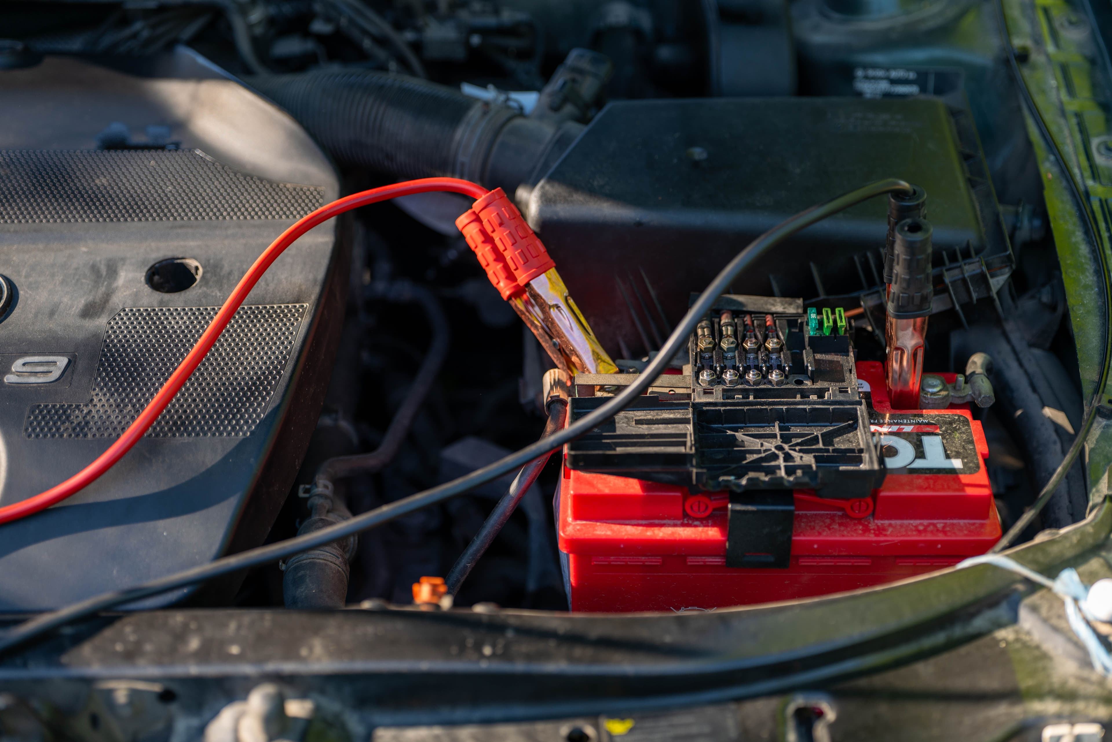 Mechanic inspecting a car engine and battery