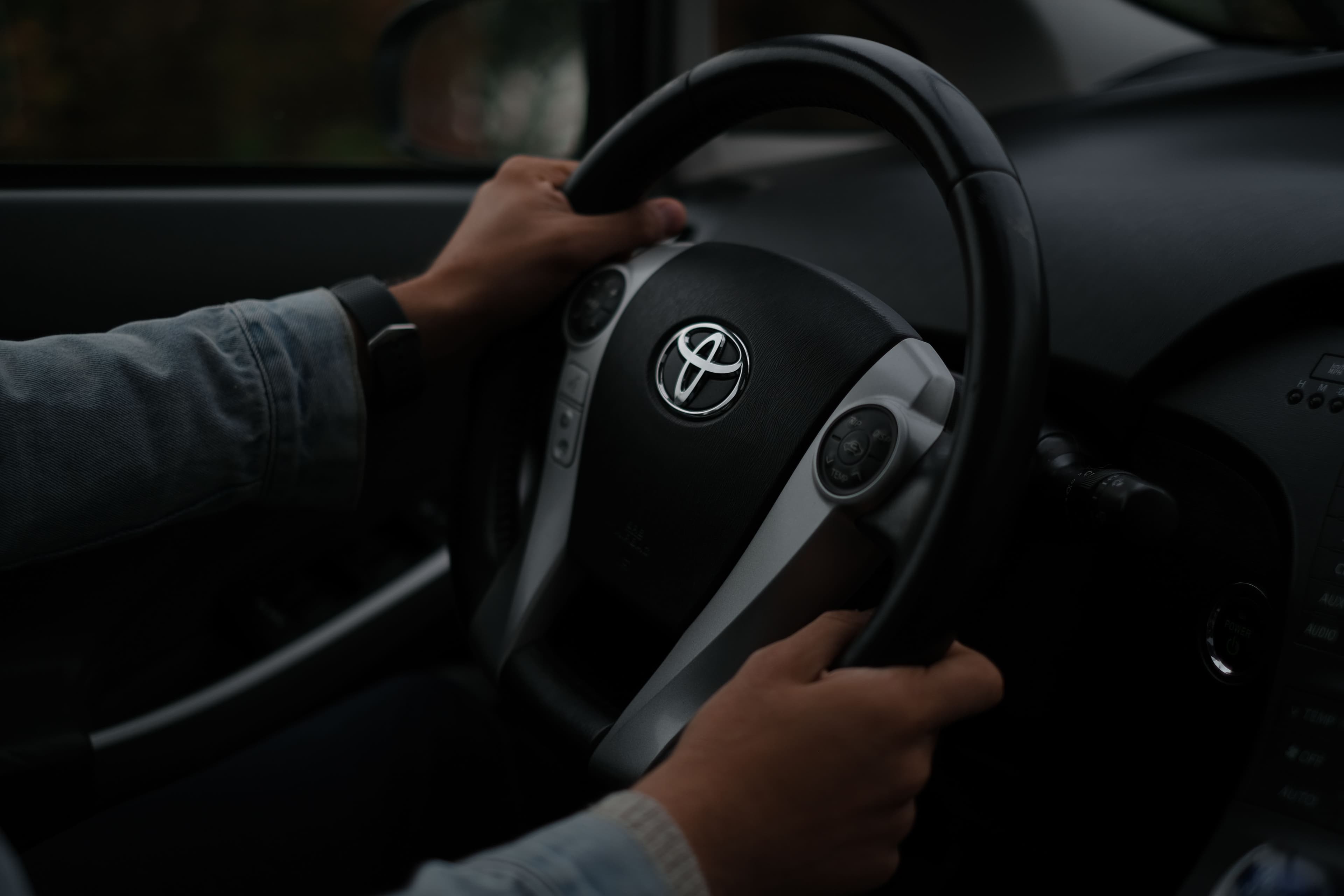 Driver's hands gripping a car steering wheel